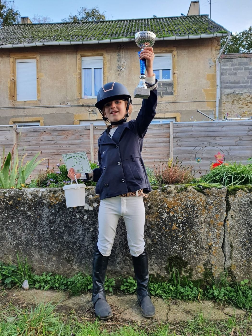 Jeune cavalière brandissant sa coupe après un concours