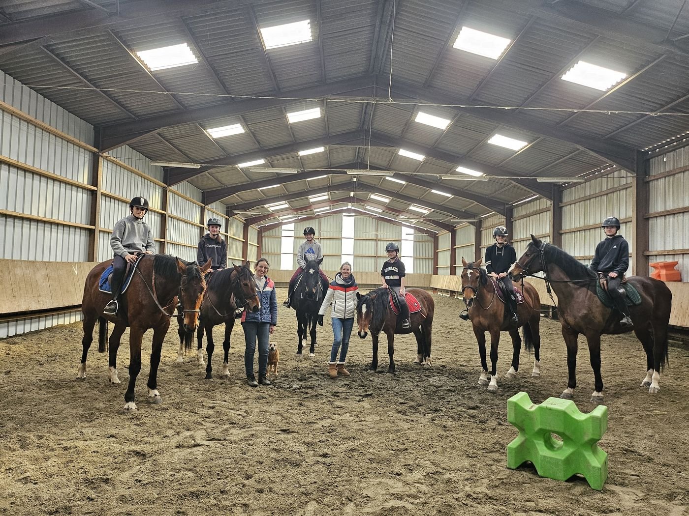 Groupe de jeunes cavaliers à cheval réunis dans un manège pendant un stage