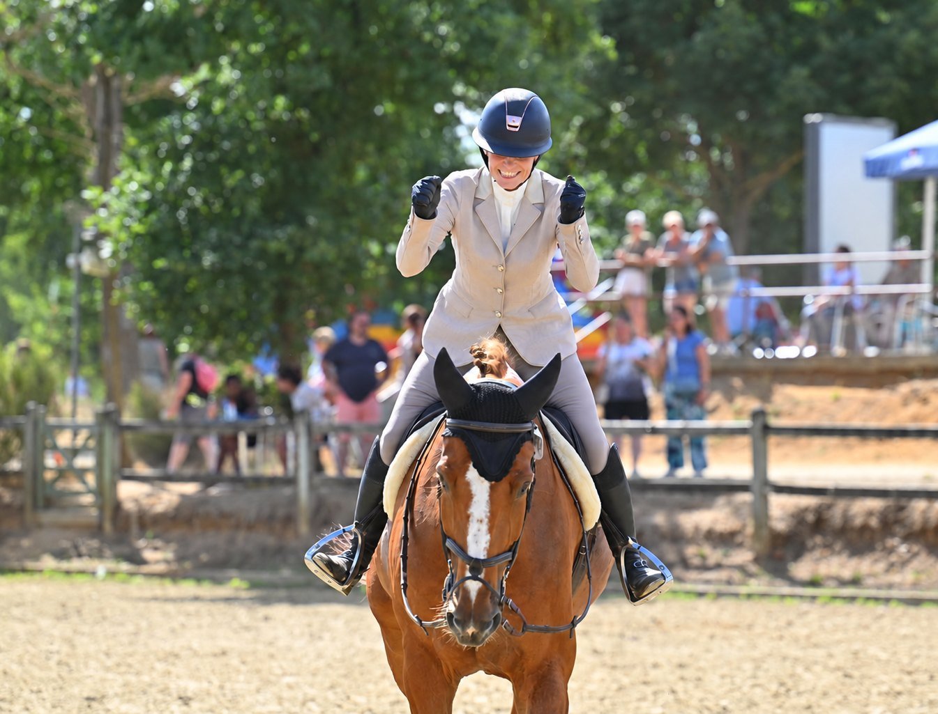 Cavalière levant les bras de joie à cheval après son parcours